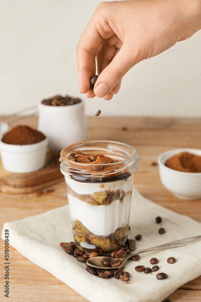 Woman making sweet tasty tiramisu at home