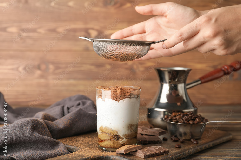 Woman making sweet tasty tiramisu at home