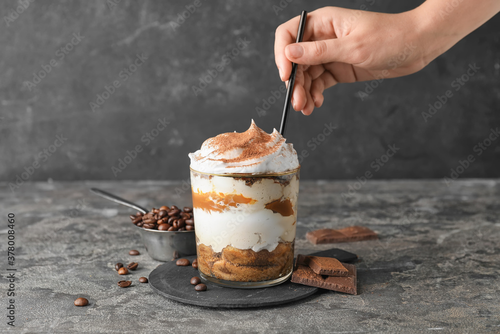 Woman eating sweet tasty tiramisu at table