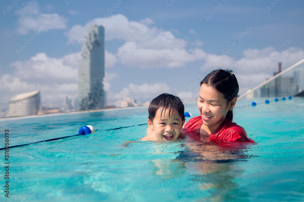 Asian Mother and baby swim in the roof top pool