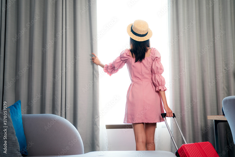 Asian woman traveller in pink dress arrive to room in hotel and open curtain