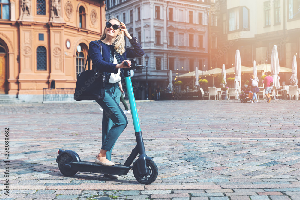 millennial woman rides electric scooter in the city streets. eco friendly transportation