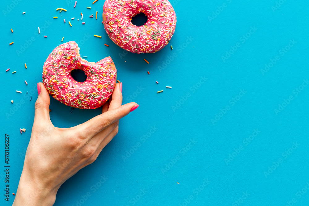 Hand holding glazed donut swith sprinkles, above view