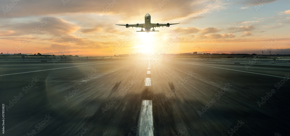 Huge commercial airplane taking off runway. Dramatic sunset light and sky on background.