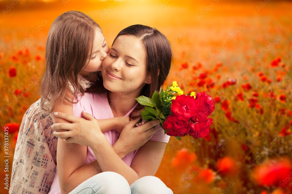 Happy beautiful mother and daughter hugging with a bouquet