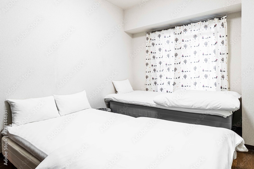 Twin beds and white blankets in a small white bedroom at a Japanese-style house