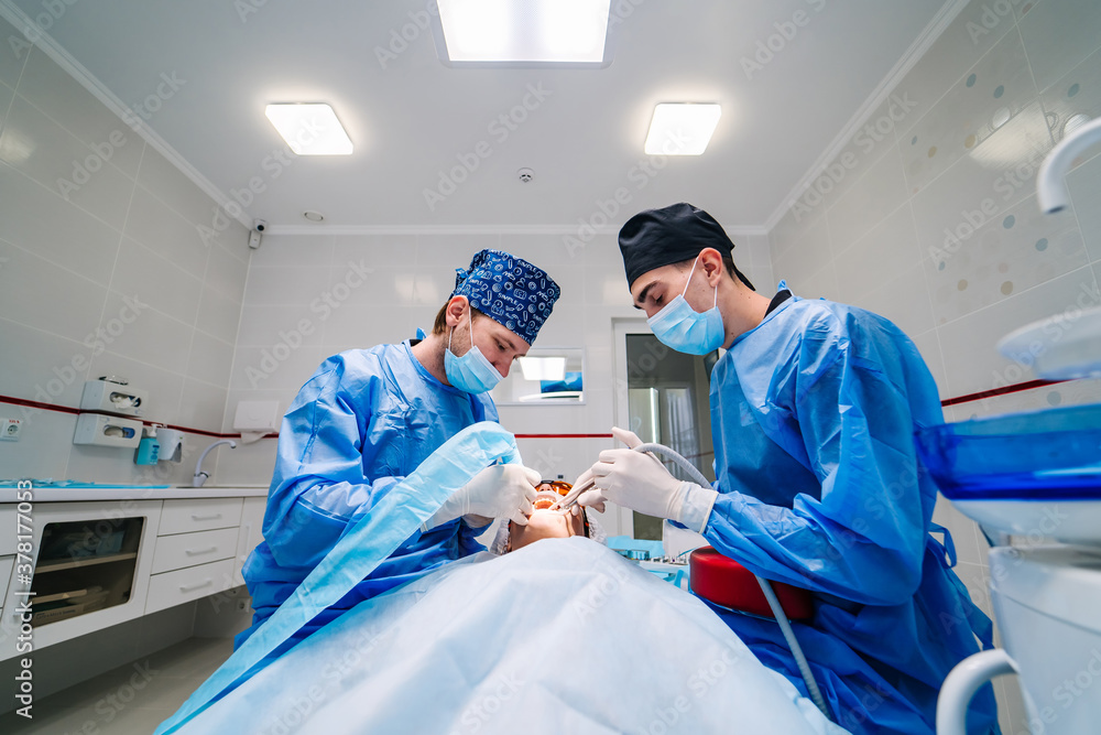 Surgery dental operation. Two dentists provide stomatology operation. Dental clinic. Selective focus