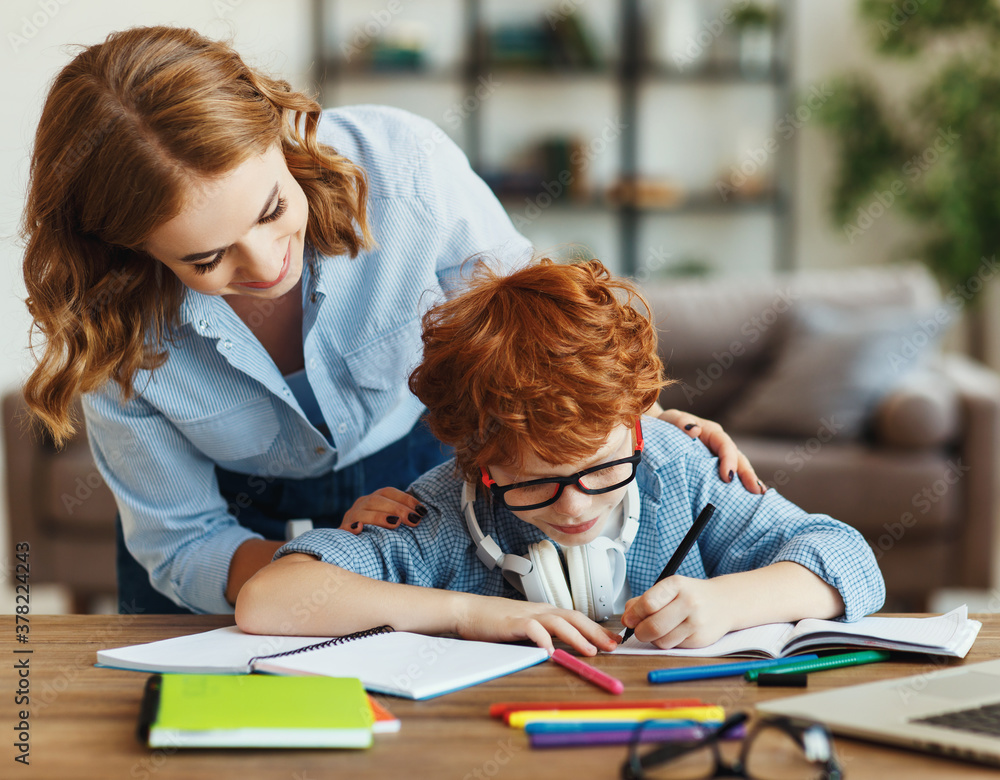 Mother helping child with homework, looks at her sons notebook at home.