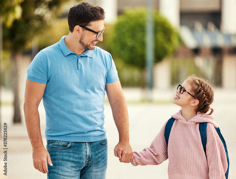 Happy father and daughter walking on street.