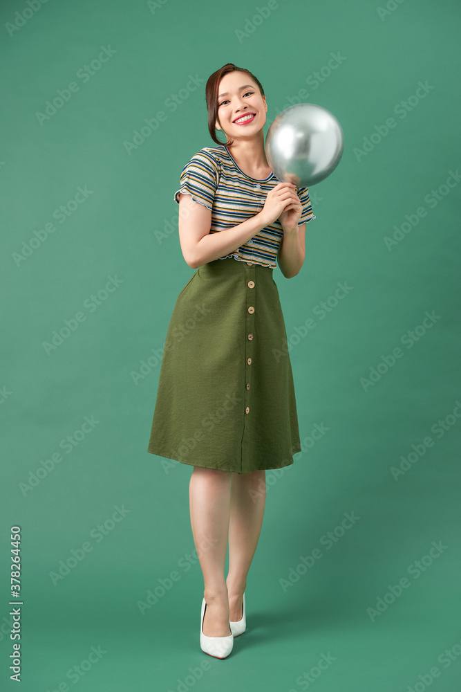 Beautiful young happy woman with smile, silver balloon on green background