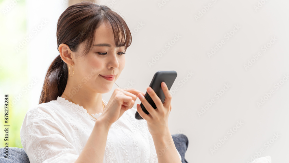 リビングでスマートフォンを使う女性