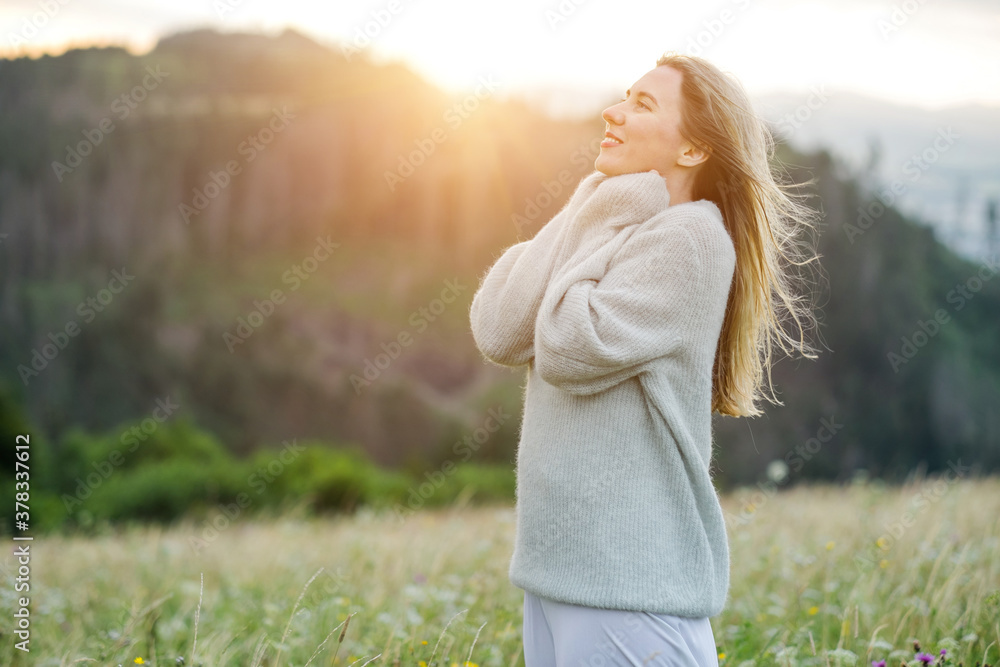 Happy woman enjoying sunset stay on the green grass on the forest peak of mountain. Fresh air, Trave