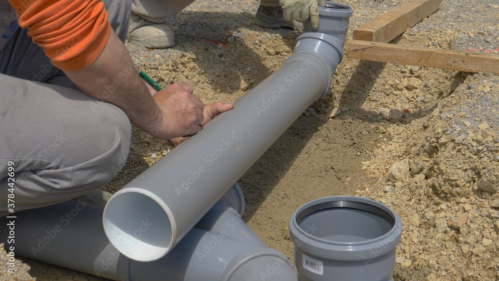 CLOSE UP: Unrecognizable builder marks a plastic sewage pipe with a pencil.