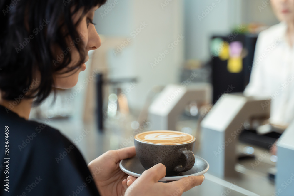 Beautiful customer in cafe restaurant holding cup of latte art coffee