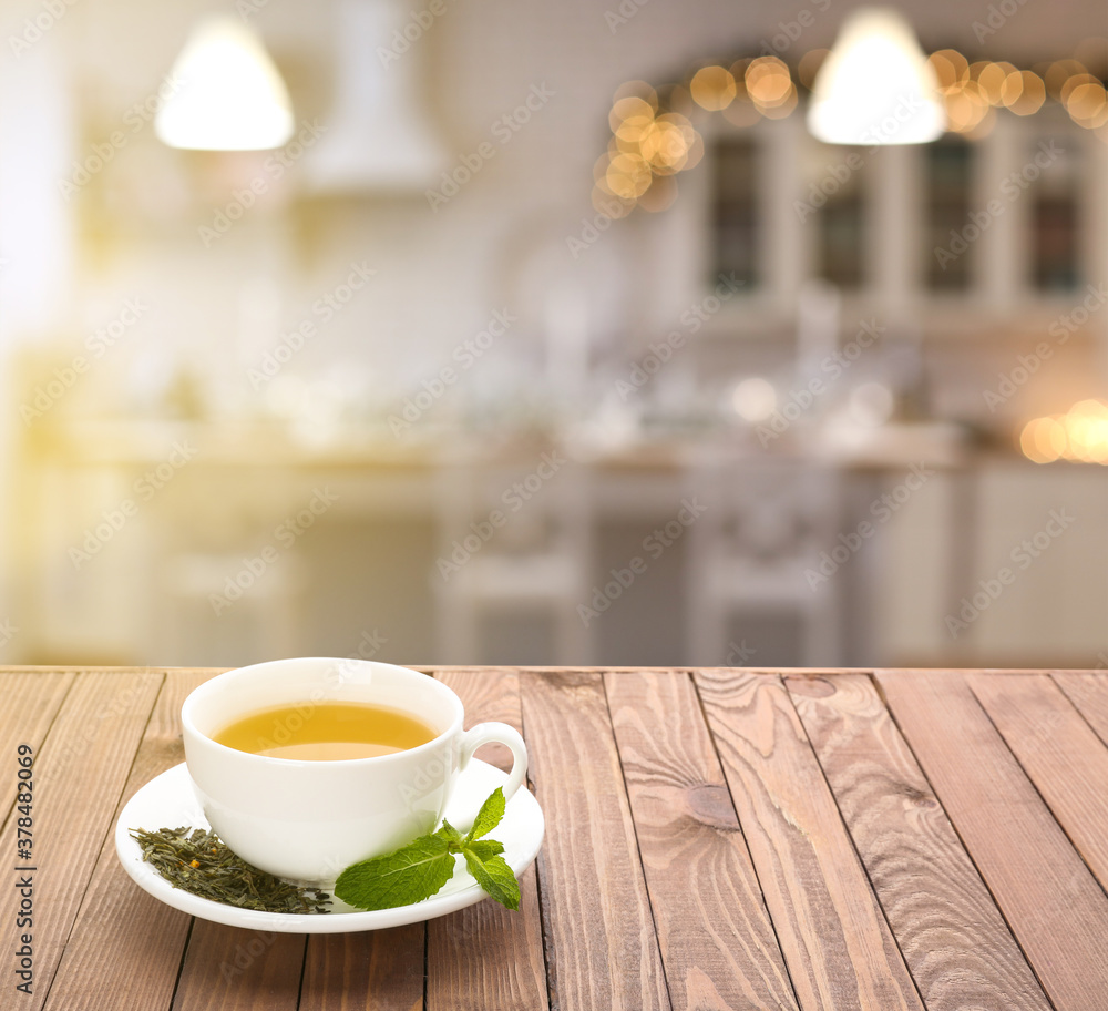 Cup of tasty tea with mint on wooden table in kitchen