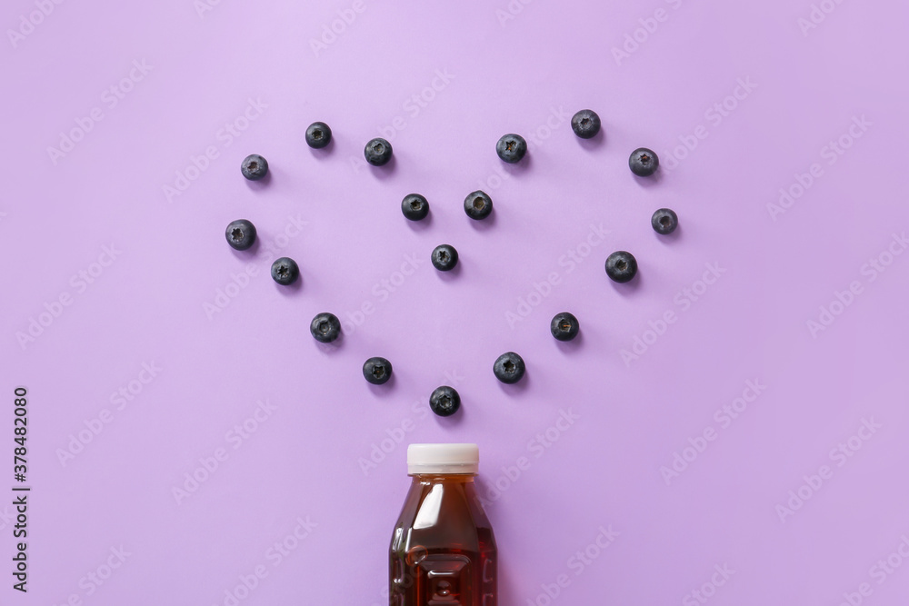 Bottle of fresh ice tea and heart made of berries on color background