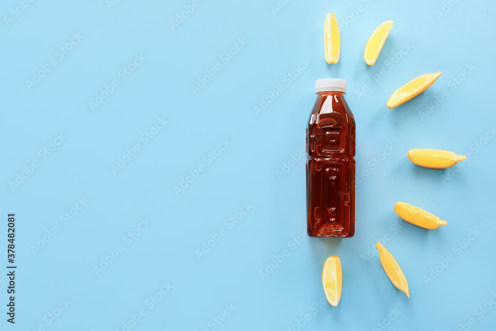 Bottle of fresh ice tea and lemon on color background