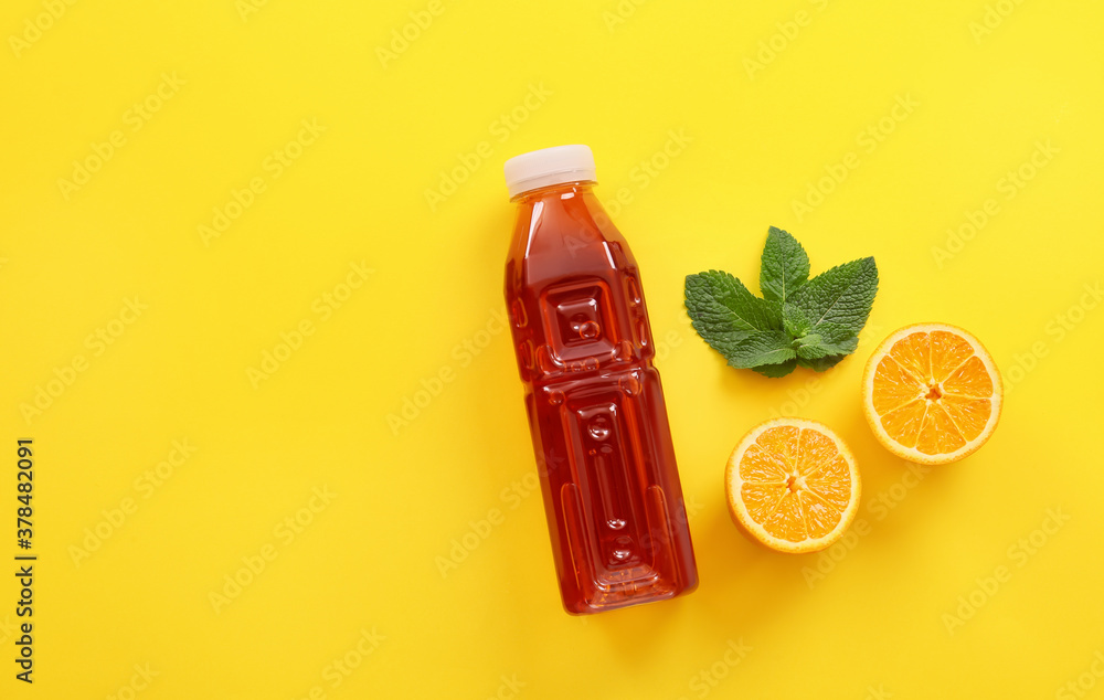 Bottle of fresh ice tea and ingredients on color background