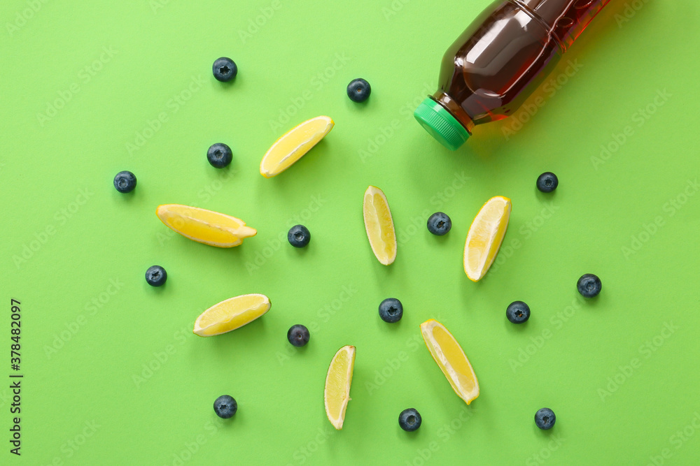 Bottle of fresh ice tea and ingredients on color background