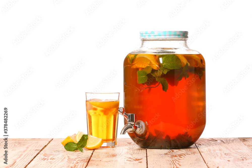 Jar and glass of fresh ice tea on table against white background