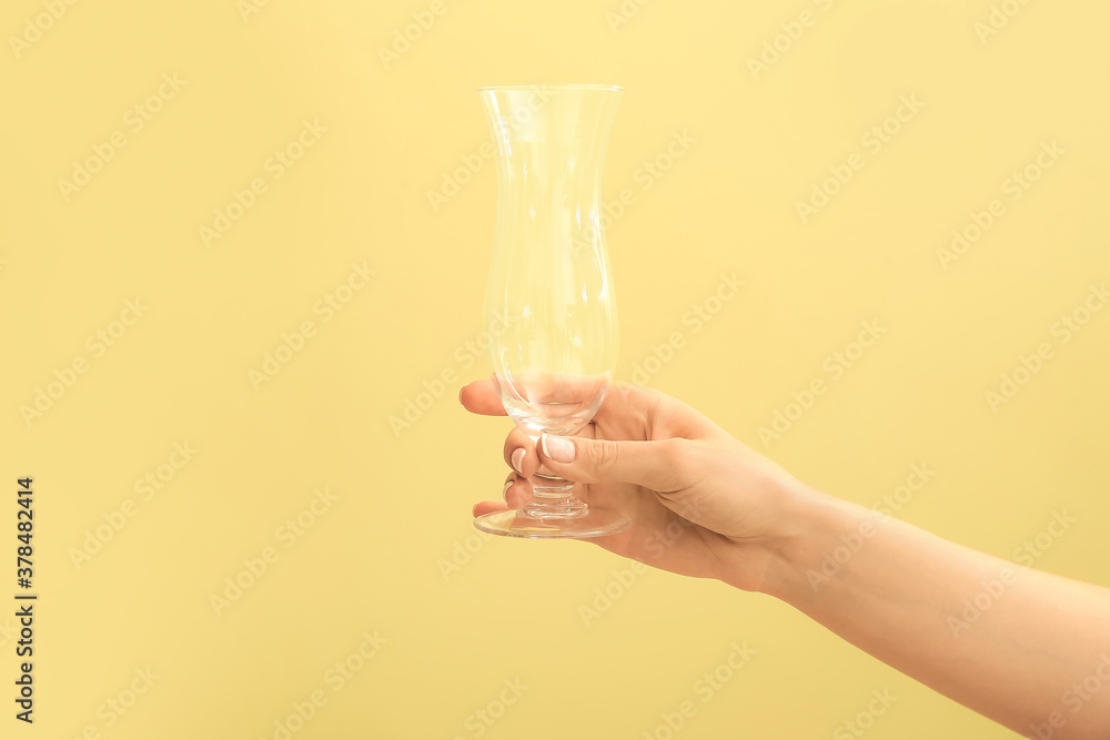 Hand with empty glass on color background