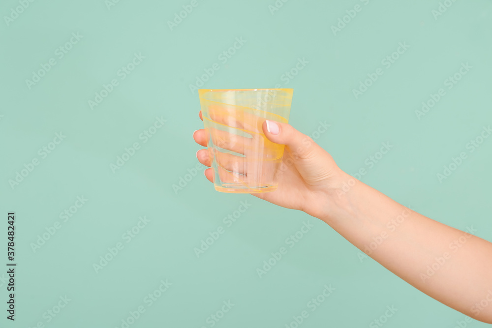 Hand with empty glass on color background