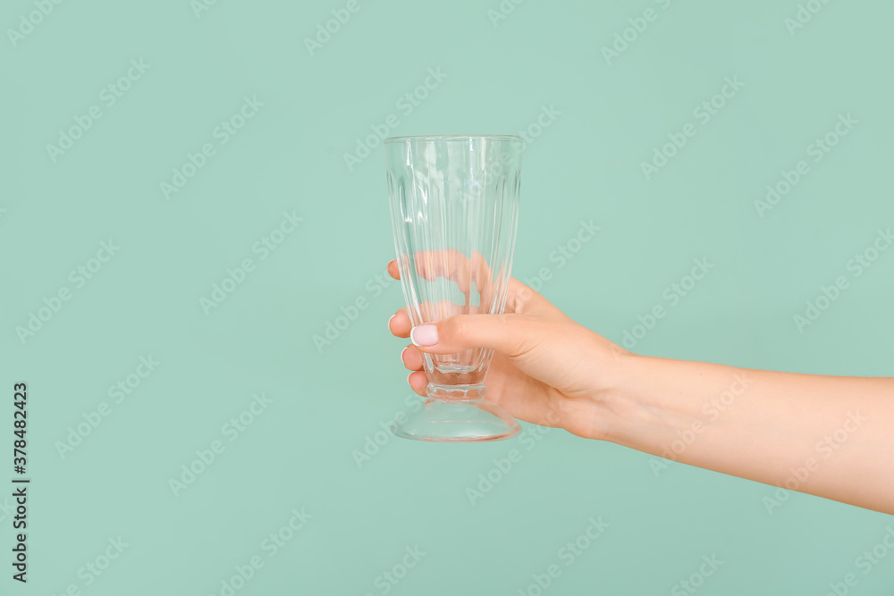 Hand with empty glass on color background