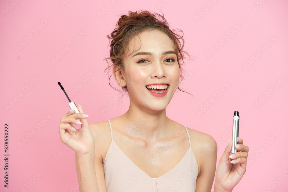 Beautiful happy girl apply mascara facial cosmetics