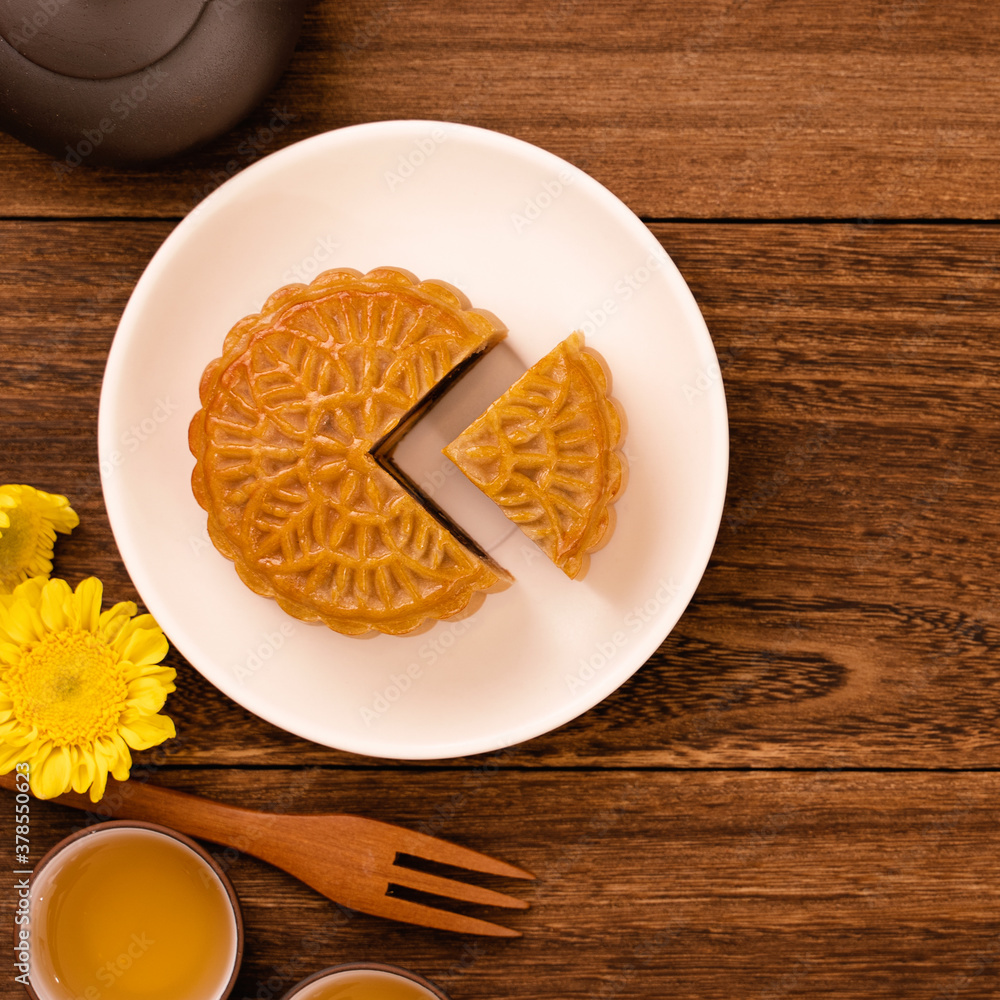 Moon cake for Mid-Autumn Festival, delicious beautiful fresh mooncake on a plate over dark wooden ba