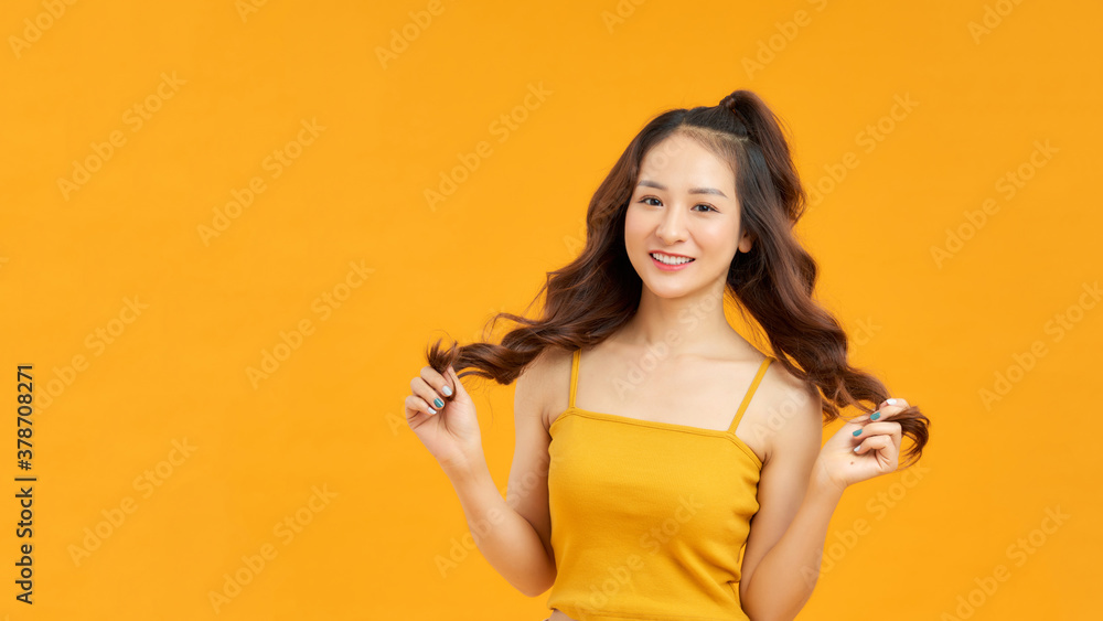 Beautiful smiling woman with clean skin, and white teeth posing on yellow background