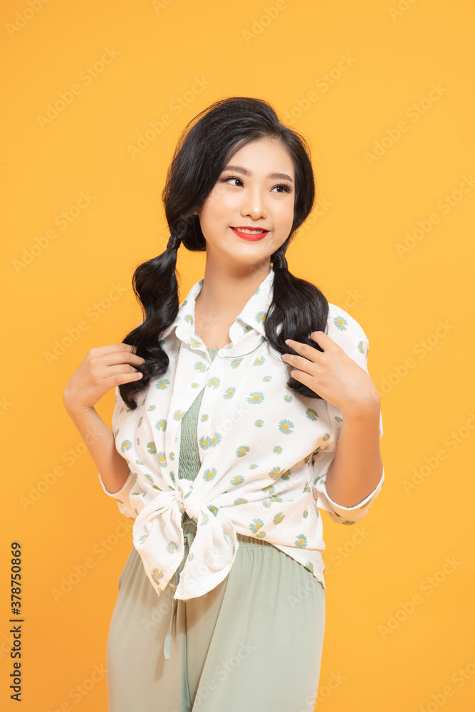 Portrait of a pretty smiling woman posing isolated on a yellow background