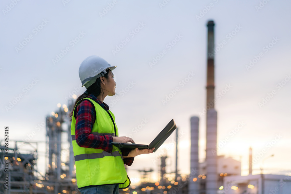 Asian woman petrochemical engineer working at night with notebook Inside oil and gas refinery plant 