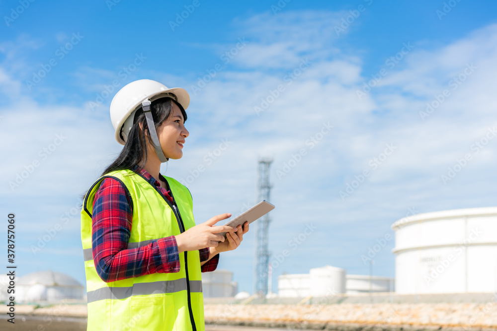 Asian woman petrochemical engineer working with digital tablet Inside oil and gas refinery plant ind