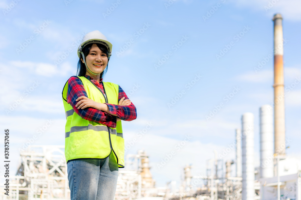 Asian woman engineer arm crossed and smile with confident looking forward to future with oil refiner