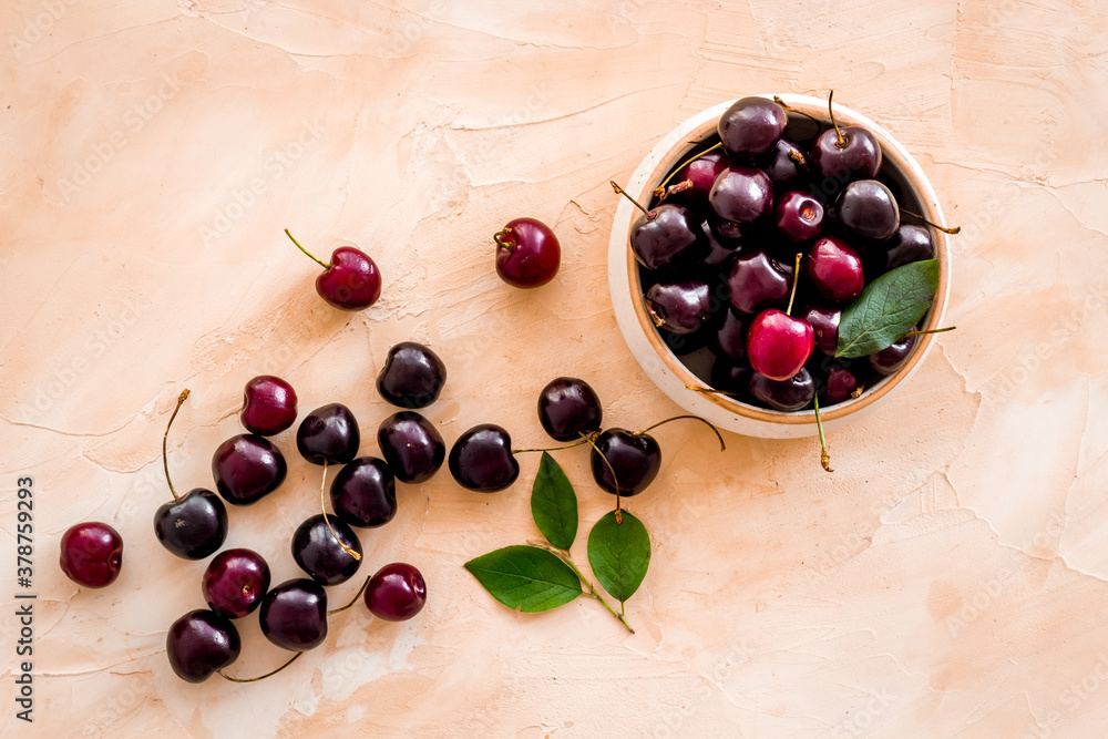 Plate of ripe red cherries with leaves, top view