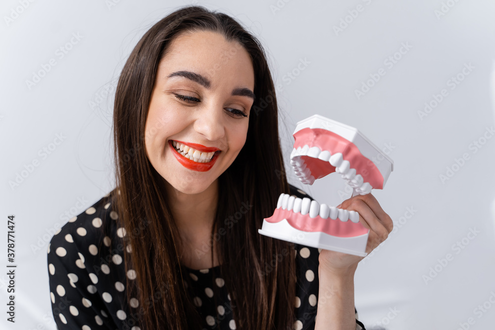 Girl looking to a dental educational jaw. Plastic jaw in girl`s hands. Funny emotions.