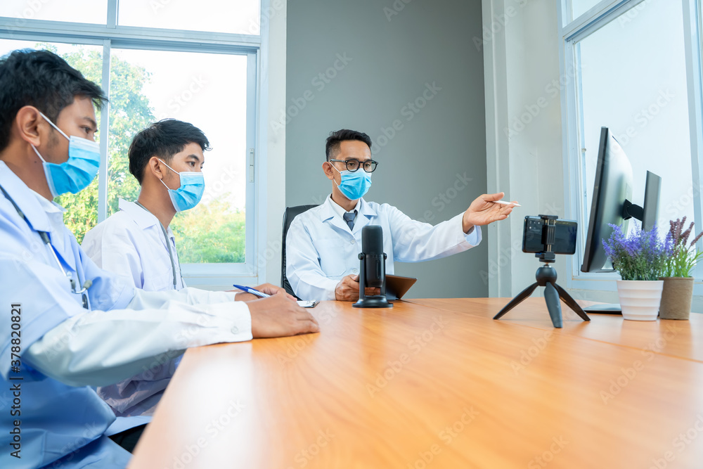 Group of doctor wearing protective surgical mask discuss work together and looking at online present