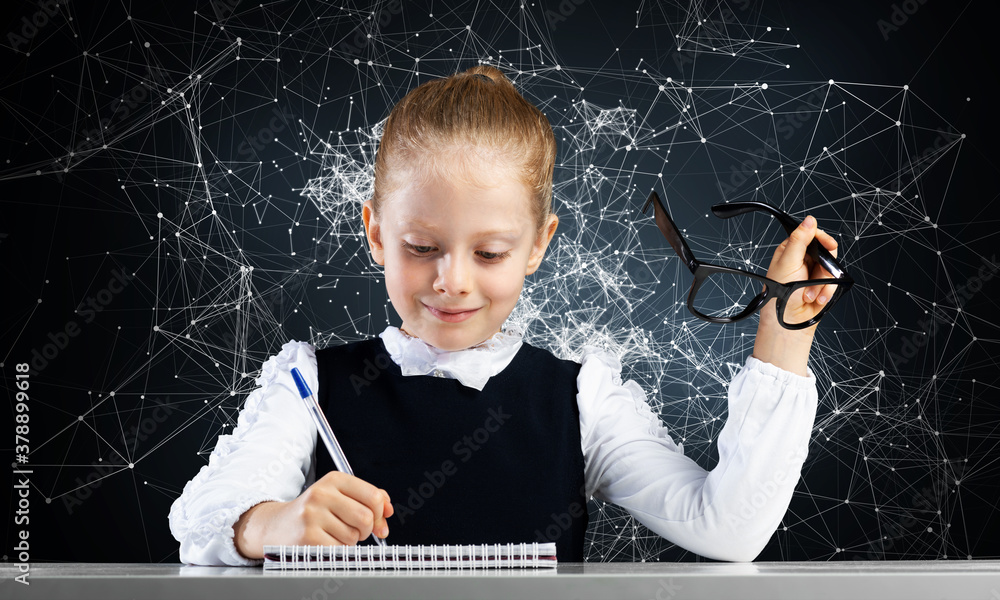 Smiling little girl in schoolwear doing homework