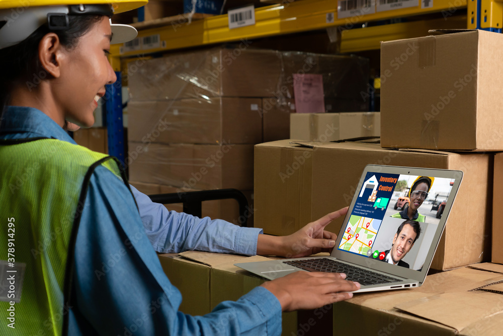 Warehouse staff talking on video call at computer screen in storage warehouse . Online software tech