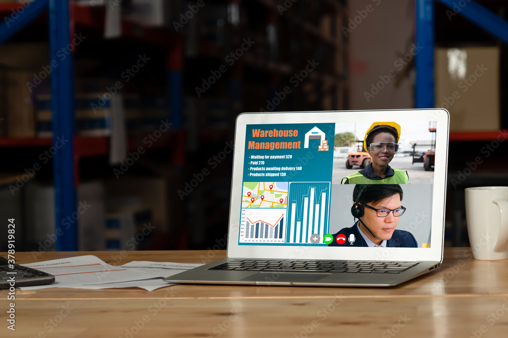 Warehouse staff talking on video call at computer screen in storage warehouse . Online software tech