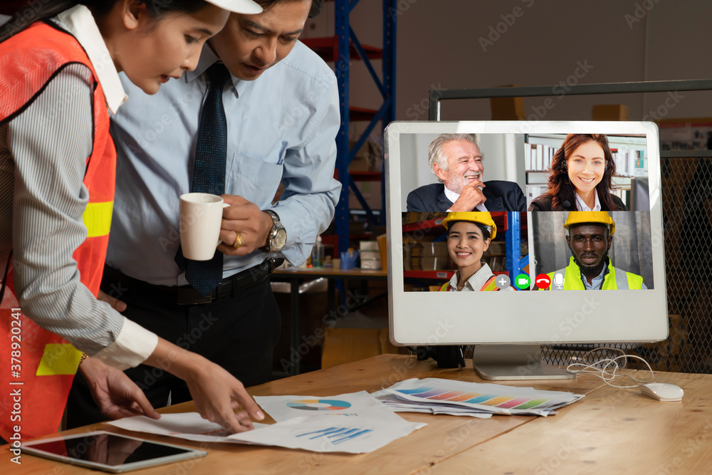 Warehouse staff talking on video call at computer screen in storage warehouse . Online software tech