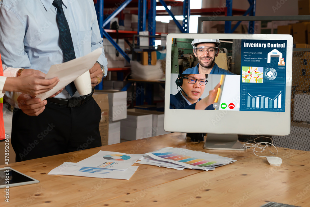 Warehouse staff talking on video call at computer screen in storage warehouse . Online software tech