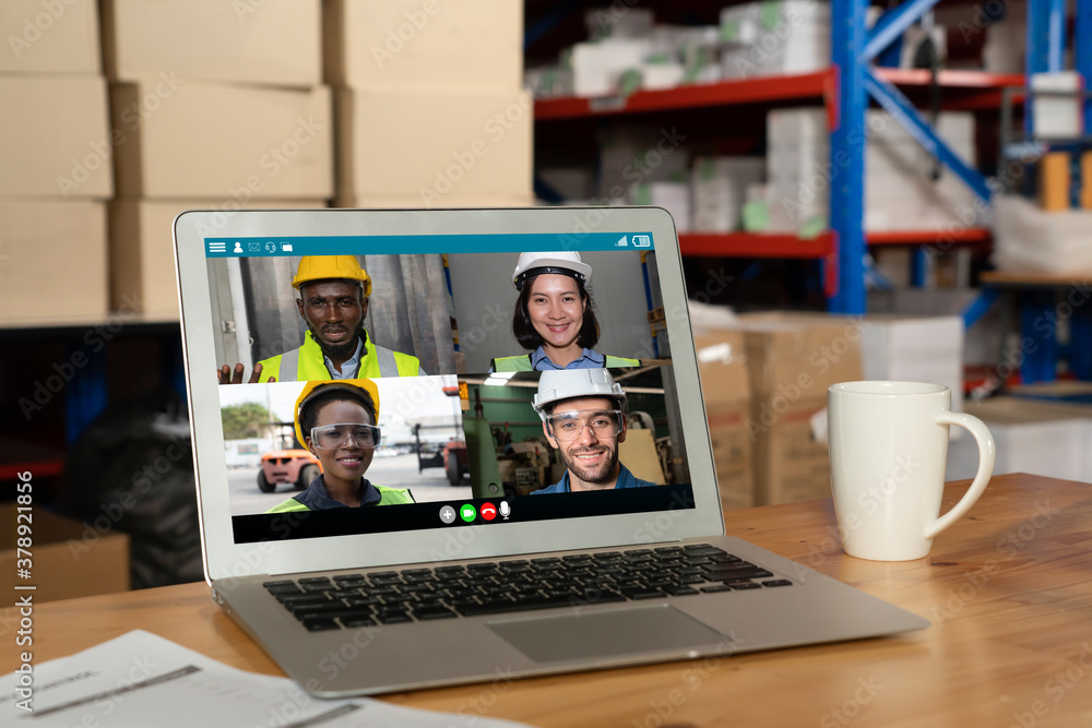 Warehouse staff talking on video call at computer screen in storage warehouse . Online software tech