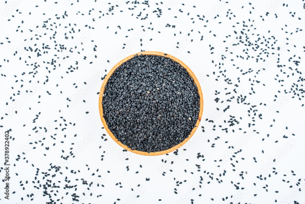 Black sesame seeds in a saucer on white background