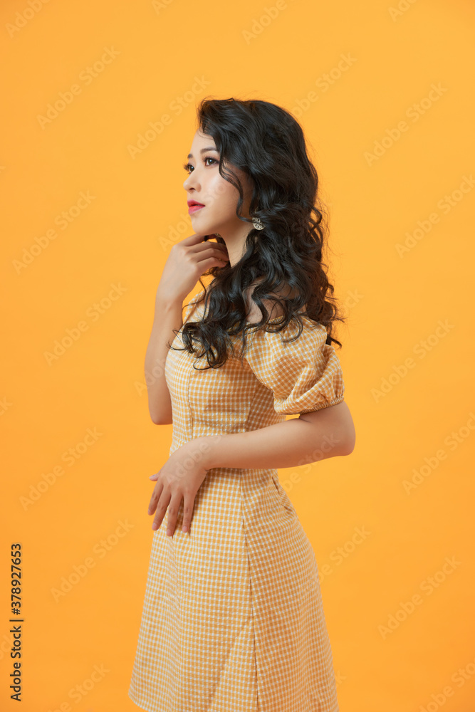 young beautiful confident girl in dress on yellow background