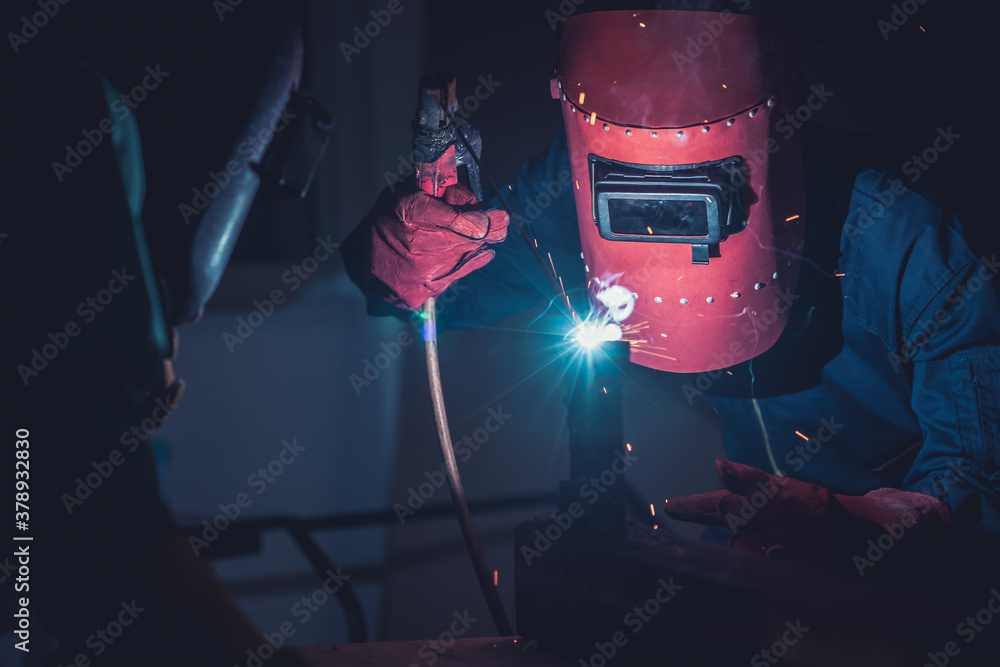 Metal welding steel works using electric arc welding machine to weld steel at factory. Metalwork man