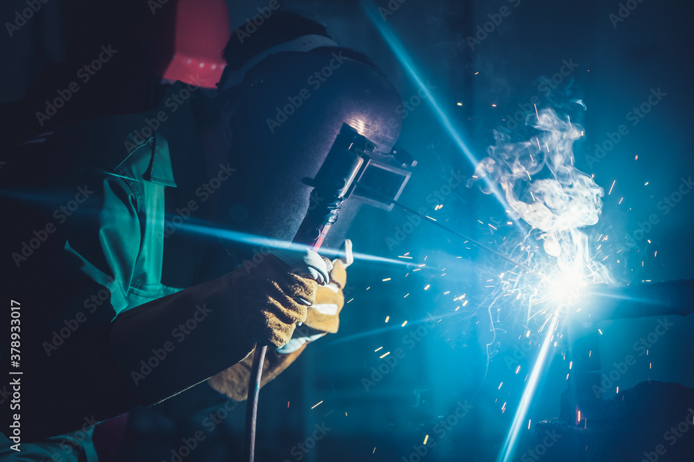 Metal welding steel works using electric arc welding machine to weld steel at factory. Metalwork man