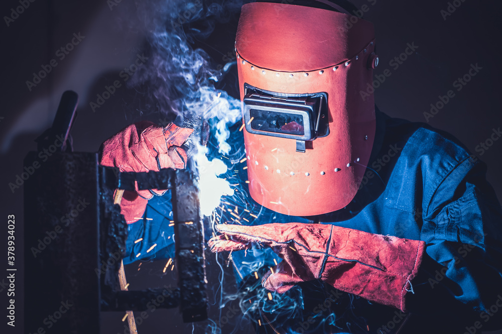 Metal welding steel works using electric arc welding machine to weld steel at factory. Metalwork man