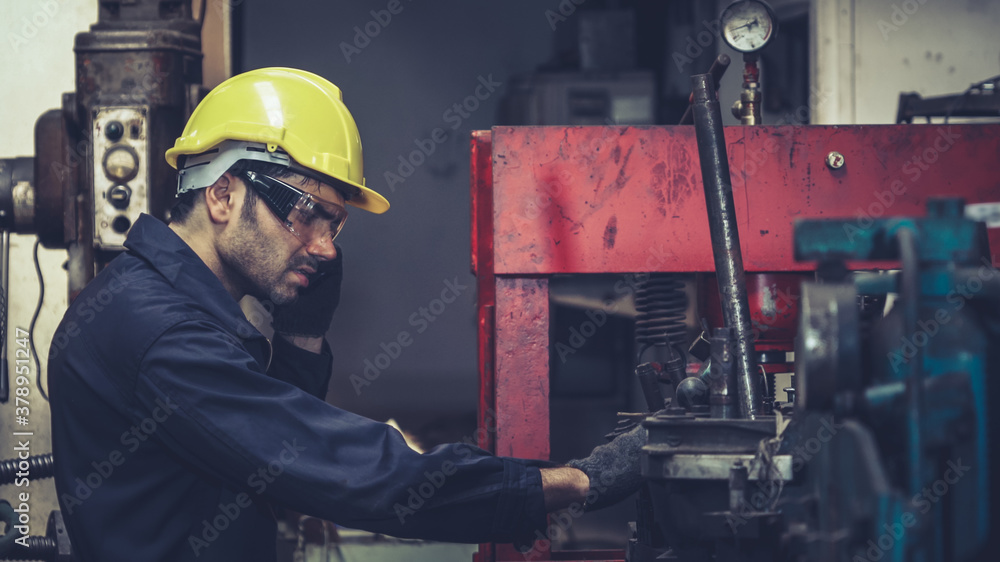 Factory worker talking on portable radio while inspecting machinery parts . Industrial and engineeri