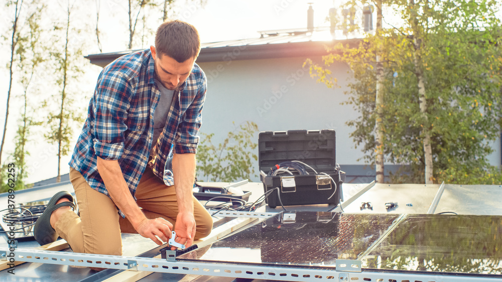 Caucasian Man in Checkered Shirt is Installing Black Reflective Solar Panels to a Metal Basis with a